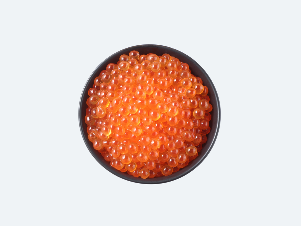 Black bowl filled with orange caviar on a white background