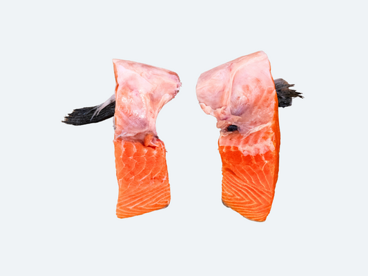 Two pieces of frozen salmon kama (collar) with visible scales and flesh, against a white background.