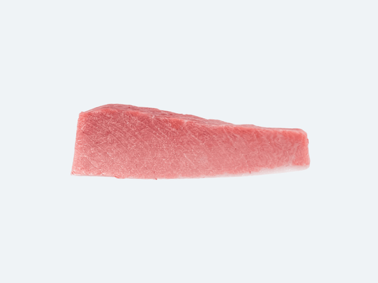 A single piece of raw bluefin tuna o-toro, cut into a rectangular shape, on a white background.